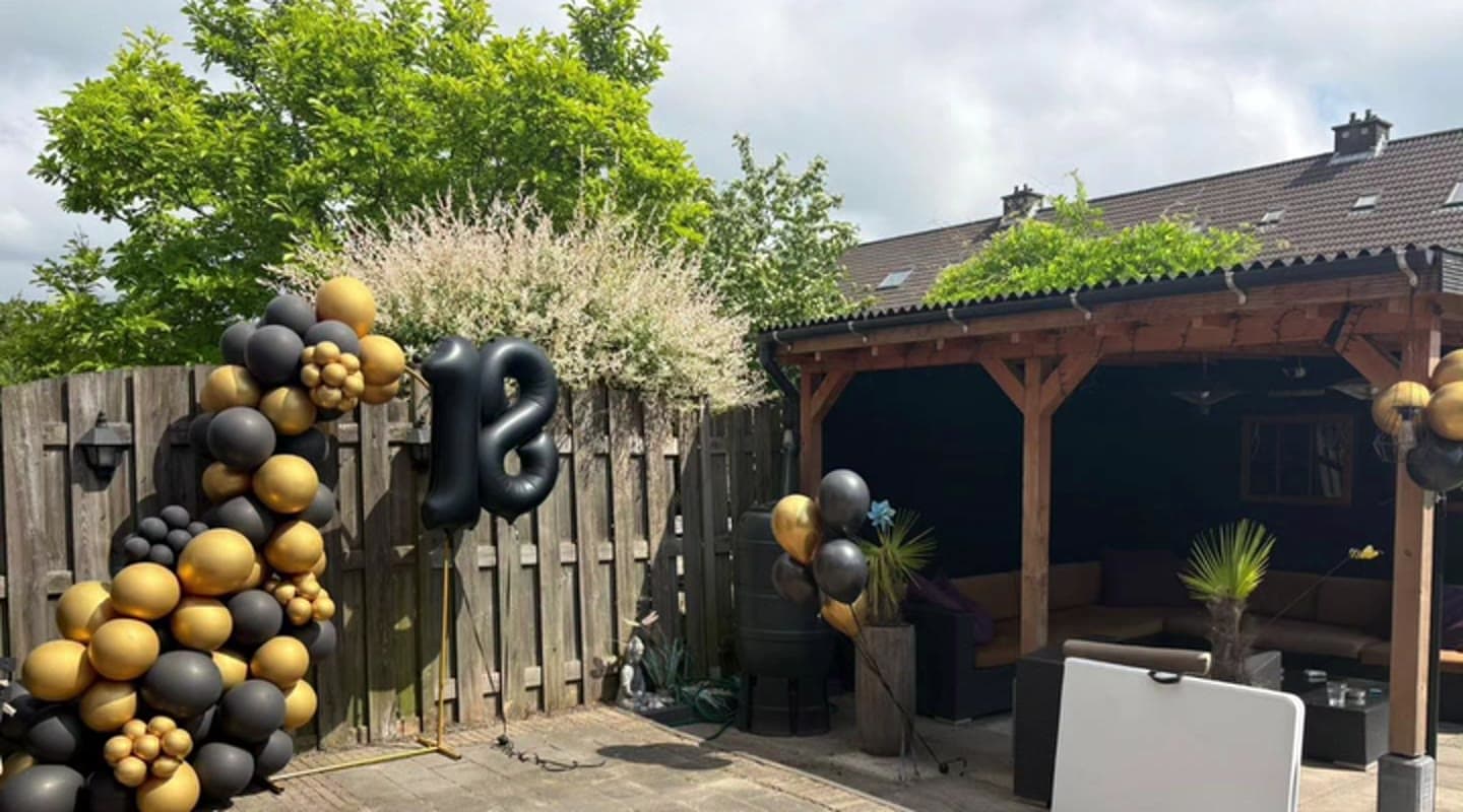 Verjaardagsfeest in de tuin met zwart-gouden ballondecoratie en cijferballon